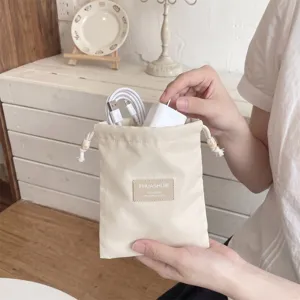 Gedetailleerd overzicht van een beige opbergtasje met trekkoord voor kabels en kleine accessoires.