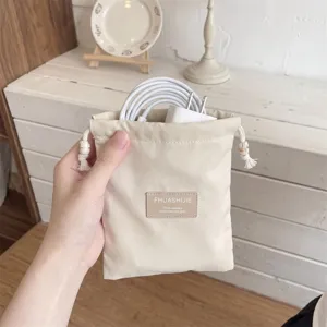 Gedetailleerd overzicht van een beige stoffen opbergzakje met trekkoord voor kabels.