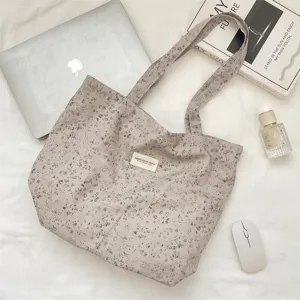 Detailansicht der ästhetischen Blumen-Segeltuchtasche mit Lifestyle-Requisiten auf weißem Grund.