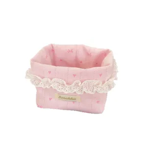 Rosa Stoff Tisch Aufbewahrungskorb mit weisser Spitzenbuerde und niedlichem Schleifen Muster.