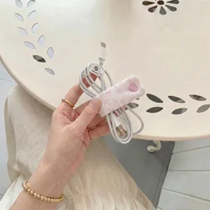 Floral cord organizer strap with pink heart snap button detail for tidy cable management.