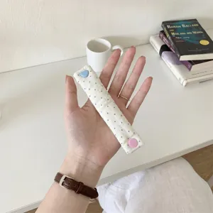 Cute polka dot earphone cable organizer strap with heart snap button for tidy desktop.