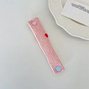 Detailed view of the red and white striped cable organizer with cute heart button for cables.