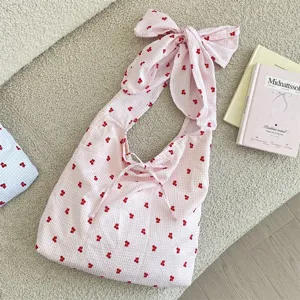Pink gingham hobo shoulder bag detail featuring a large decorative bow strap and cute red pattern.
