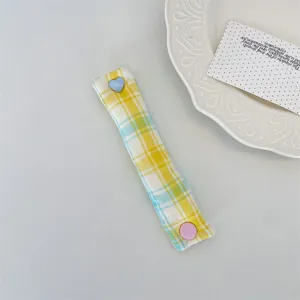 Macaron plaid cable organizer detail, cute heart button earphone cord strap for tidy desk.