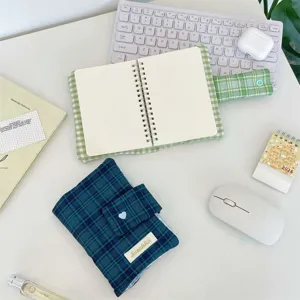 Detailed top-down view of green plaid planner cover, desktop stationery setup, snap button.