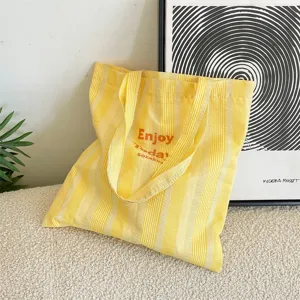 Detailansicht der gelb-weiß gestreiften Canvas-Tasche mit strukturiertem Stoff und Schulterriemen.