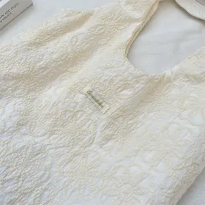 Sac à épaule en toile brodé blanc crème, cabas décontracté sous les bras au design floral texturé.