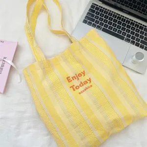 Gelb-weiße gestreifte Canvas-Tasche Detail mit Strukturstoff und lässigem Alltagsdesign.