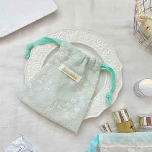 Joli pochette cordon en gaze vert menthe brodée de fleurs pour bijoux et rouge à lèvres.