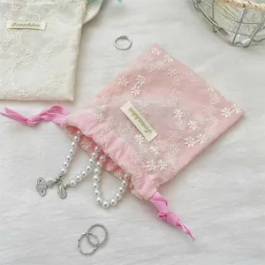 Pochette rose brodée à cordon de serrage, idéale pour le rangement de bijoux et accessoires élégants.