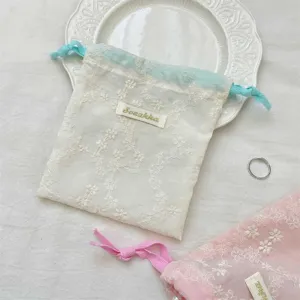 Détail de pochette à cordon en tulle brodé de fleurs, sac de rangement bijoux et maquillage.