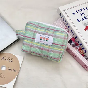 Primo piano di una trousse di bellezza trapuntata a quadri pastello con manico ed etichetta.