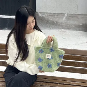 Close-up detail of green plush handbag with blue floral pattern, cute winter fuzzy tote bag.