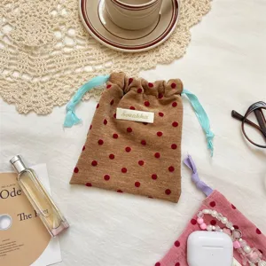 Close-up detail of the brown velvet polka dot drawstring pouch with contrasting blue cords.