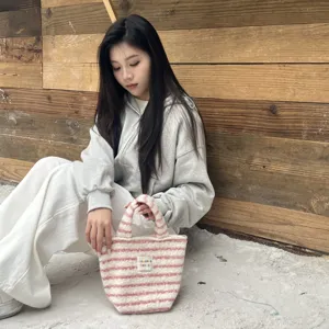 Detailed view of the pink and white striped fuzzy handbag displayed in a cozy setting.