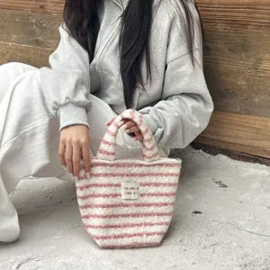 Detail view of the pink and white striped plush handbag with soft texture and handles.