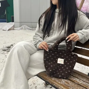 Close-up detail of winter brown plush handbag with small white tag on soft fluffy fabric.