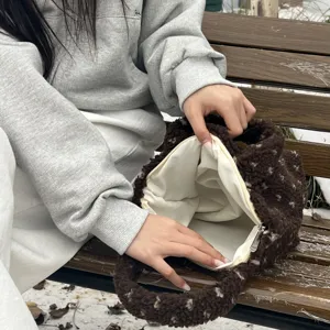 Detailed view of winter brown fluffy plush handbag with zipper and white lining interior.