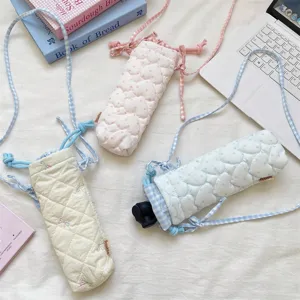 Detailed view of the quilted camera bag with heart pattern, drawstring and grid strap.