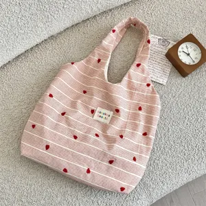Detailed view of striped canvas tote bag with red heart embroidery and cute aesthetic design.