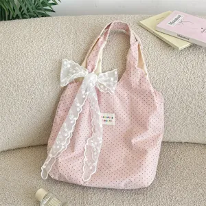 Pink polka dot canvas tote bag with elegant white lace bow detail for daily casual use.