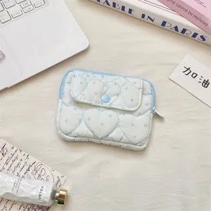 Detailed close-up shot of light blue quilted heart pattern coin purse with snap closure.