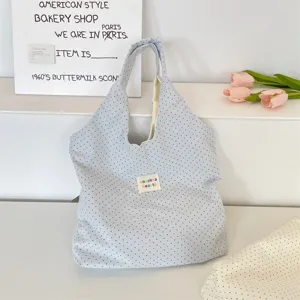 Detailed view of casual blue polka dot canvas tote bag with woven label, clean backdrop.