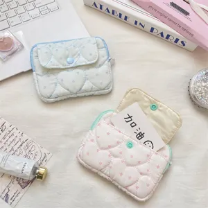 Detailed shot of quilted heart card pouch with snap button closure, cute lifestyle flat lay.
