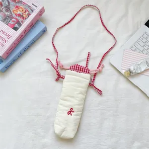 Detailed close-up of the quilted camera bag featuring red check straps and cute bow embroidery.