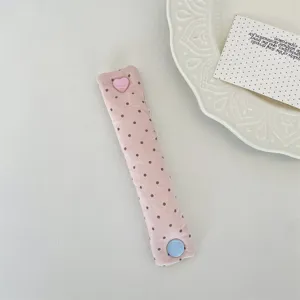 Details of pink polka dot cord organizer featuring cute heart and round snap buttons.
