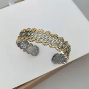 Brazalete abierto elegante con diseño de malla de panal, bordes dorados y circonitas brillantes.