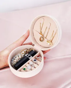 Primer plano del joyero redondo portátil con compartimentos y ranuras para anillos.