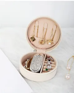 Caja de almacenamiento de joyas redonda portátil con compartimentos para anillos.