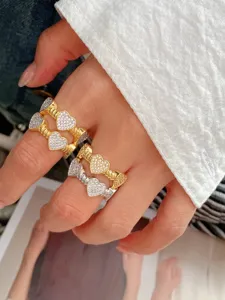 Gros plan détaillé de bagues cœur en zircon bicolore avec un élégant bandeau torsadé.