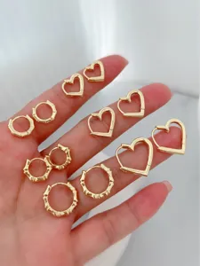 Detailed close-up of gold bamboo hoop and minimalist heart earrings showcasing exquisite metal design.