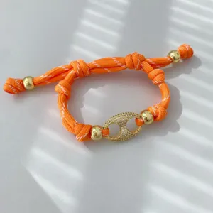 Nahaufnahme Detail des luxuriösen orange gewebten Armbands mit funkelndem Zirkonia-Verschluss.