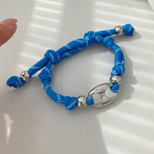 Detail des blauen geflochtenen Armbands mit silbernen Metallperlen und Schweinenase-Charm.