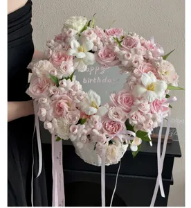 Dettaglio cesto di fiori con specchio a cuore, rose rosa e nastro per confezionamento bouquet.