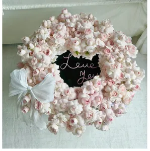 Corona di fiori con specchio a forma di cuore con rose rosa e fiocco bianco per regali.
