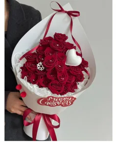 Splendido bouquet di rose rosse di Natale con carta da regalo bianca e decorazioni festive.
