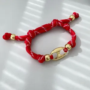 Handgefertigtes rot-weißes geflochtenes Armband mit goldenen Metallperlen und Anker-Anhänger.