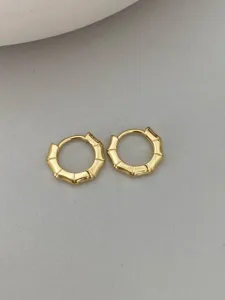 Close-up view of elegant gold bamboo joint hoop earrings, minimalist fashion metal jewelry.