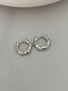 Detailed close-up of silver bamboo hoop earrings, minimalist metal jewelry design.