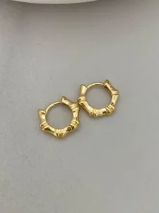 Detailed close-up of minimalist gold bamboo hoop earrings, elegant and chic jewelry design.