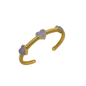 Bracelet manchette plaqué or avec trois cœurs en zirconium pavé et design torsadé.