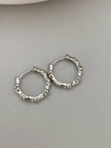 Close-up detail of silver bamboo hoop earrings, glossy metallic finish for daily wear.