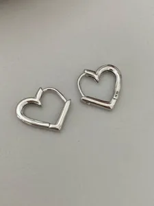 Detailed close-up of silver bamboo heart huggie earrings, minimalist and elegant design.