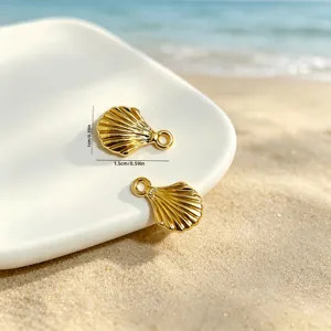 Detailed close-up of gold ocean shell charms on sand with size markings in cm and inches