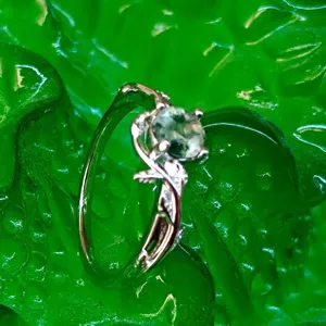 Close-up detail shot of silver moss agate ring with delicate vine leaf design.